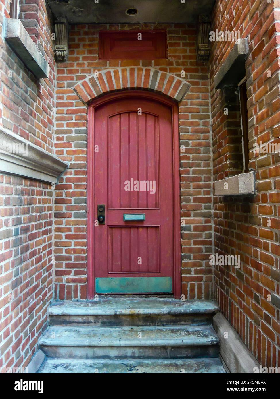 Porte rouge dans un renfoncement à l'arrière d'un bâtiment en brique Banque D'Images