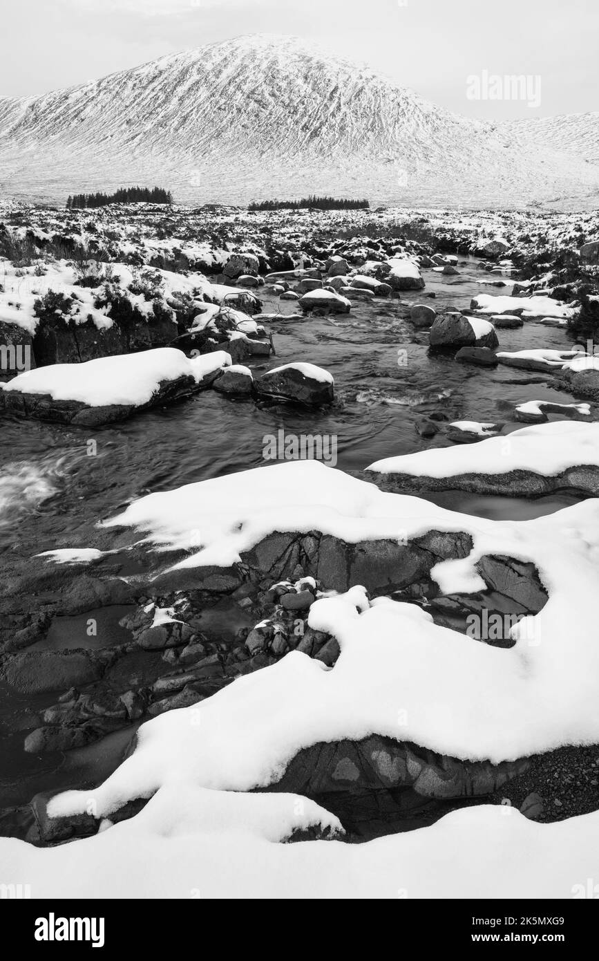 Noir et blanc magnifique paysage d'hiver de la rivière Etive en premier plan avec la montagne légendaire de Stob Dearg Buachille Etive Mor dans le b Banque D'Images