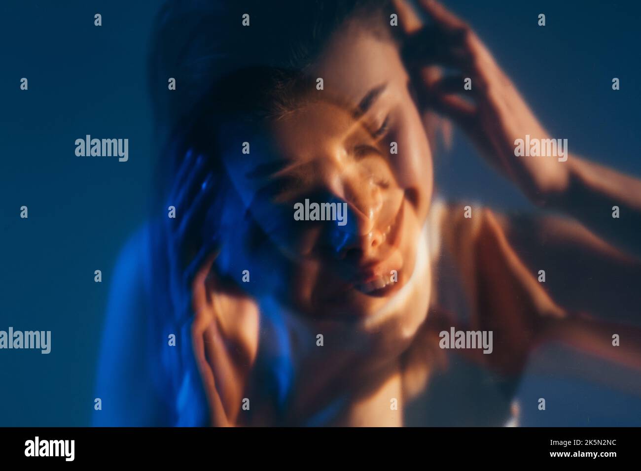 Paix intérieure. Face à double exposition. Énergie positive. Silhouette défocarée d'une femme tranquille et souriante inspirée isolée sur fond bleu foncé. Banque D'Images