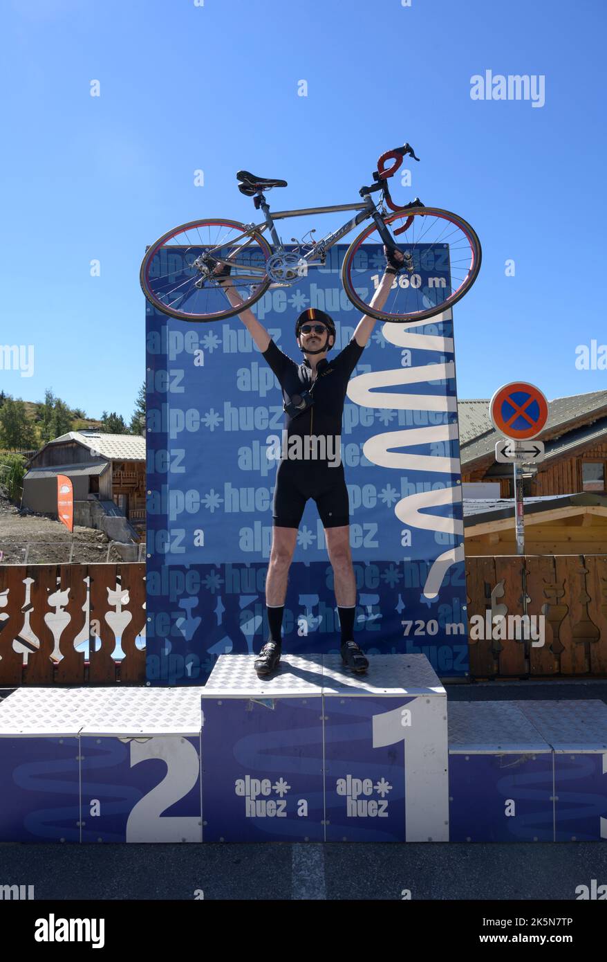 Cycliste de route masculin célébrant sa première ascension de la célèbre montée en vélo de l'Alpe d'Huez dans les Alpes françaises. Banque D'Images