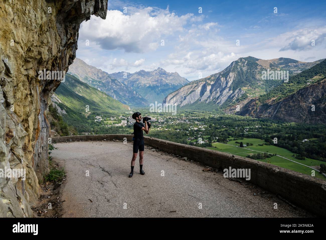 Cycliste de route mâle photographiant la route du balcon de Bourg d'Oisans à Villard notre Dame, Alpes françaises. Banque D'Images
