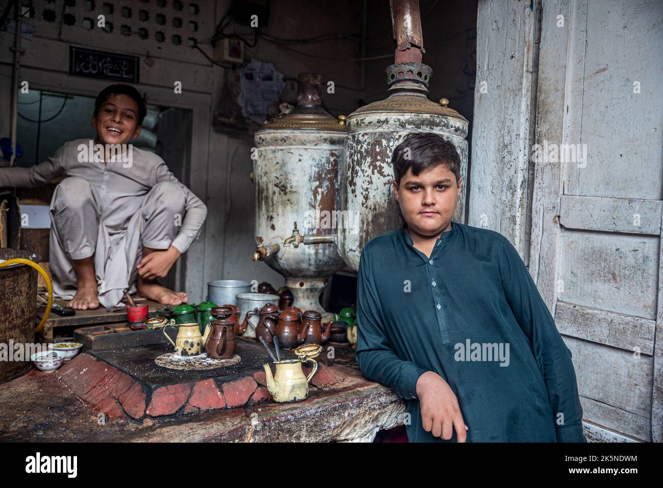 Un jeune vendeur de thé avec un client, Peshawar, province de Khyber Pakhtunkhwa, Pakistan Banque D'Images