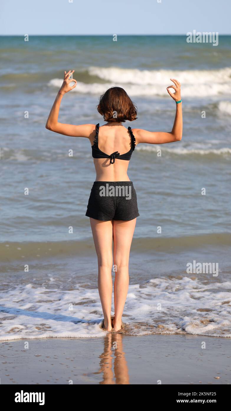 jeune fille pieds nus en maillot de bain des exercices de méditation en écartant ses bras sur la mer Banque D'Images