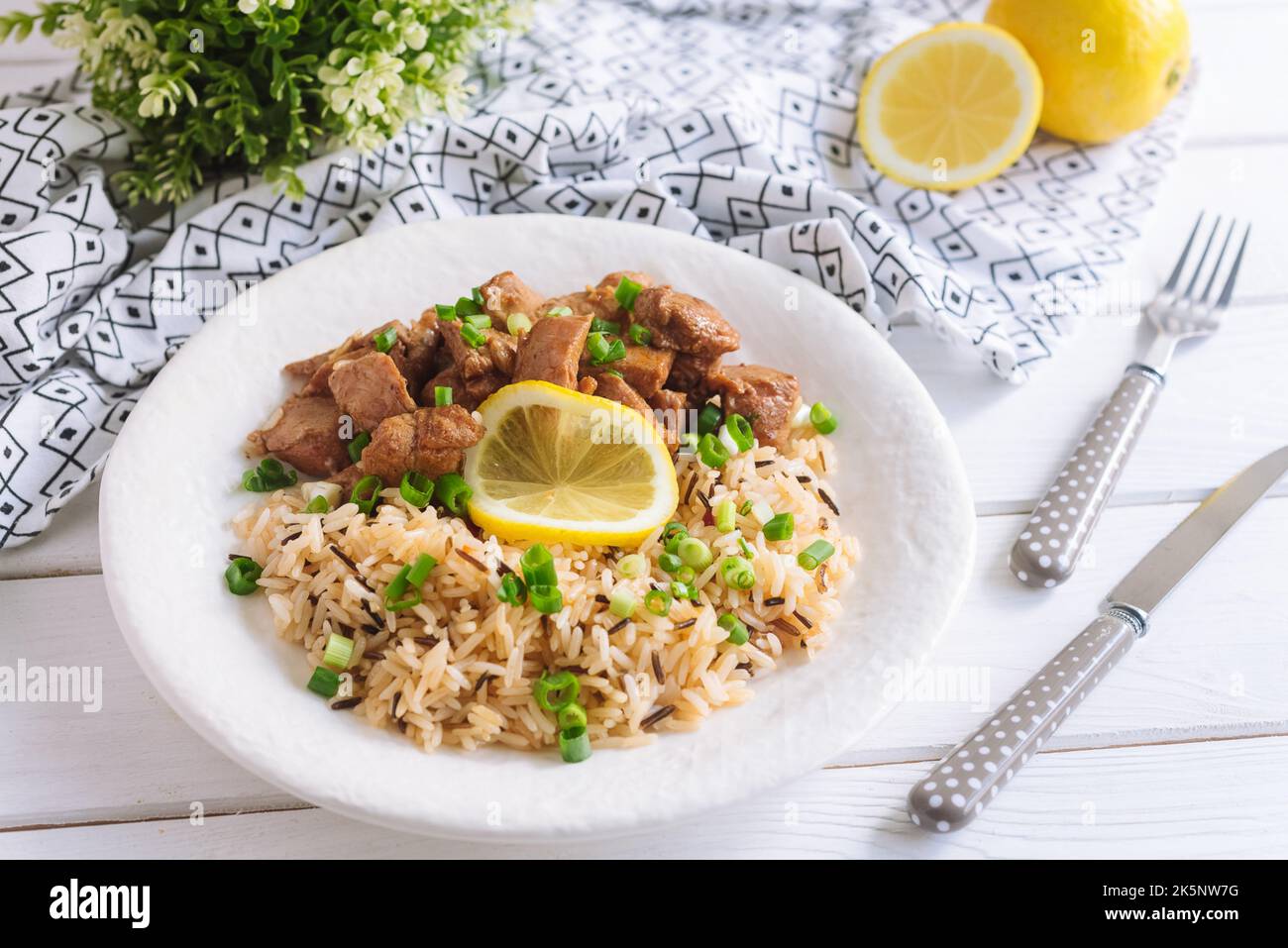 Gros morceaux de porc à côté du riz cuit à grain long, arrosé d'oignons verts hachés et d'une tranche de citron. Un délicieux déjeuner copieux Banque D'Images