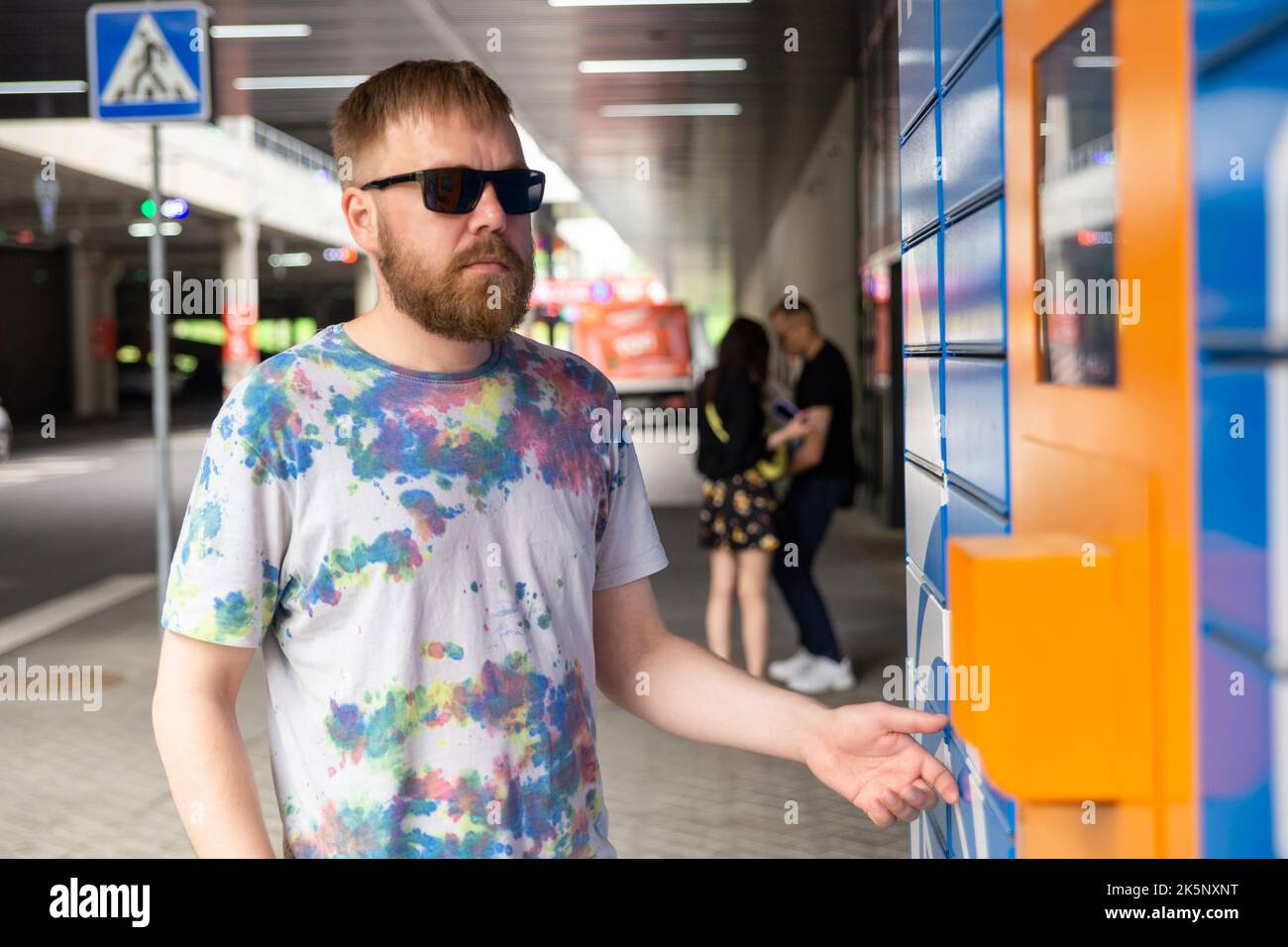 L'homme saisit le code de colis à l'écran et récupère le colis à partir de la machine postale automatisée. Man tient son smartphone à l'aide d'un terminal de messagerie automatique en libre-service cl Banque D'Images