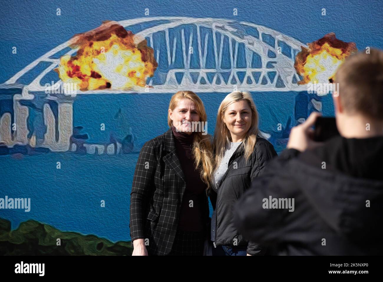 Kiev, Ukraine. 09th octobre 2022. Les gens sont photographiés avec un modèle de timbre représentant le pont en feu de Crimée en arrière-plan, dans le centre de Kiev. Sur 8 octobre, une explosion s'est produite sur le pont de Crimée construit par la Russie reliant la Russie à la péninsule de Crimée occupée par lui, endommageant une partie de la structure du pont. (Photo par Oleksii Chumachenko/SOPA Images/Sipa USA) crédit: SIPA USA/Alay Live News Banque D'Images