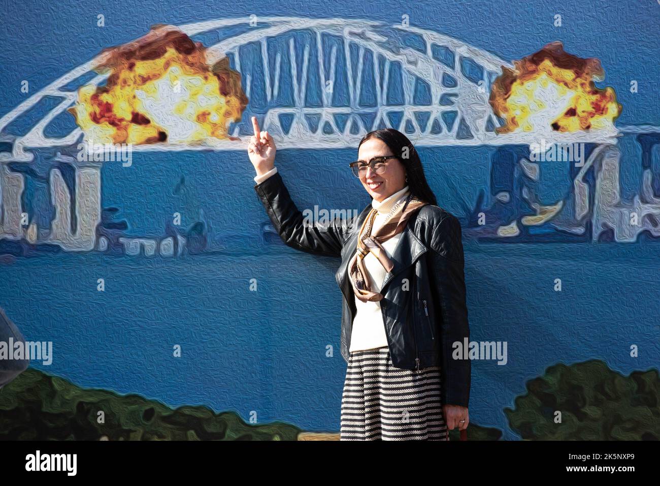 Kiev, Ukraine. 09th octobre 2022. Une femme pose pour une photo avec un modèle de timbre représentant le pont de Crimée en feu en arrière-plan, dans le centre de Kiev. Sur 8 octobre, une explosion s'est produite sur le pont de Crimée construit par la Russie reliant la Russie à la péninsule de Crimée occupée par lui, endommageant une partie de la structure du pont. (Photo par Oleksii Chumachenko/SOPA Images/Sipa USA) crédit: SIPA USA/Alay Live News Banque D'Images
