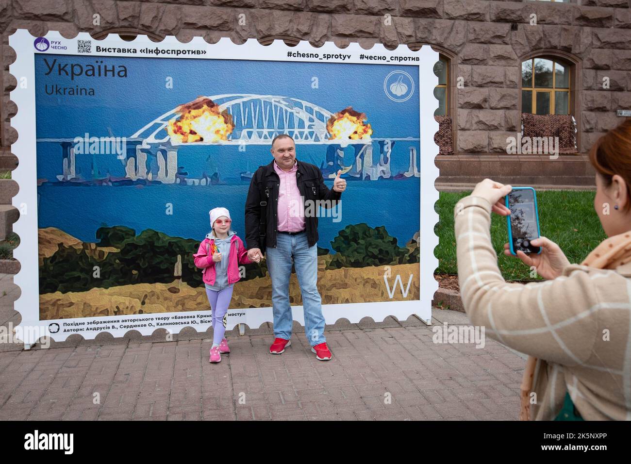 Kiev, Ukraine. 09th octobre 2022. Les gens posent pour une photo avec un modèle de timbre représentant le pont en feu de Crimée en arrière-plan, dans le centre de Kiev. Sur 8 octobre, une explosion s'est produite sur le pont de Crimée construit par la Russie reliant la Russie à la péninsule de Crimée occupée par lui, endommageant une partie de la structure du pont. (Photo par Oleksii Chumachenko/SOPA Images/Sipa USA) crédit: SIPA USA/Alay Live News Banque D'Images