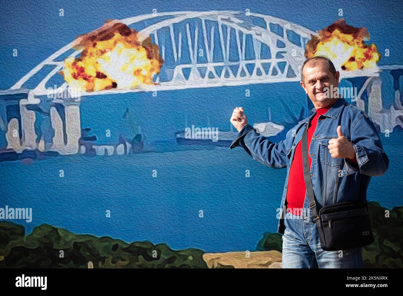 Kiev, Ukraine. 09th octobre 2022. Un homme pose pour une photo avec un modèle de timbre représentant le pont en feu de Crimée en arrière-plan, dans le centre de Kiev. Sur 8 octobre, une explosion s'est produite sur le pont de Crimée construit par la Russie reliant la Russie à la péninsule de Crimée occupée par lui, endommageant une partie de la structure du pont. (Photo par Oleksii Chumachenko/SOPA Images/Sipa USA) crédit: SIPA USA/Alay Live News Banque D'Images