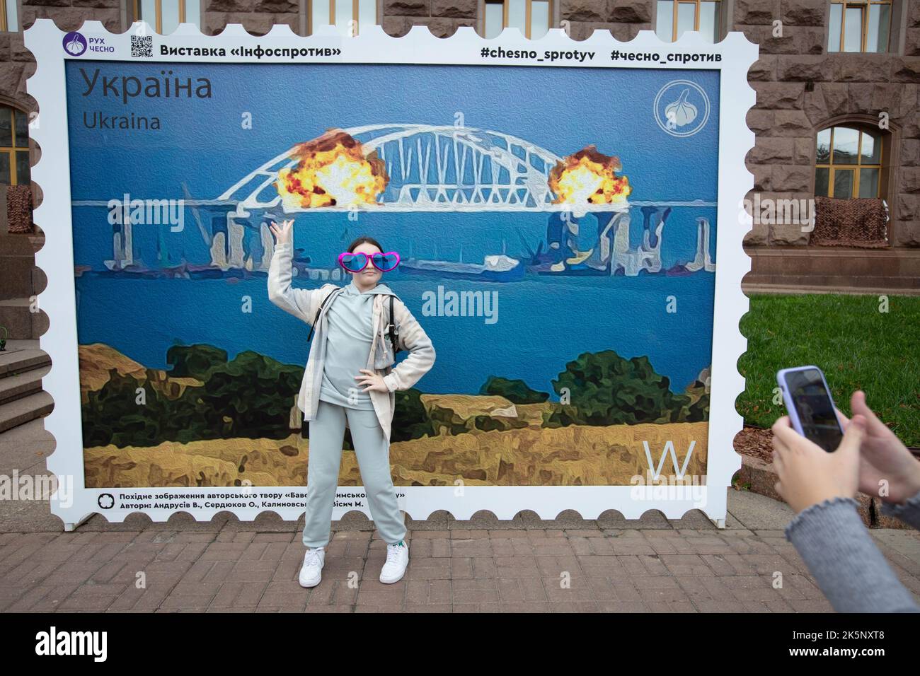 Kiev, Ukraine. 09th octobre 2022. Une fille pose pour une photo devant une maquette d'un timbre représentant le pont de Crimée en feu en arrière-plan, dans le centre de Kiev. Sur 8 octobre, une explosion s'est produite sur le pont de Crimée construit par la Russie reliant la Russie à la péninsule de Crimée occupée par lui, endommageant une partie de la structure du pont. (Photo par Oleksii Chumachenko/SOPA Images/Sipa USA) crédit: SIPA USA/Alay Live News Banque D'Images