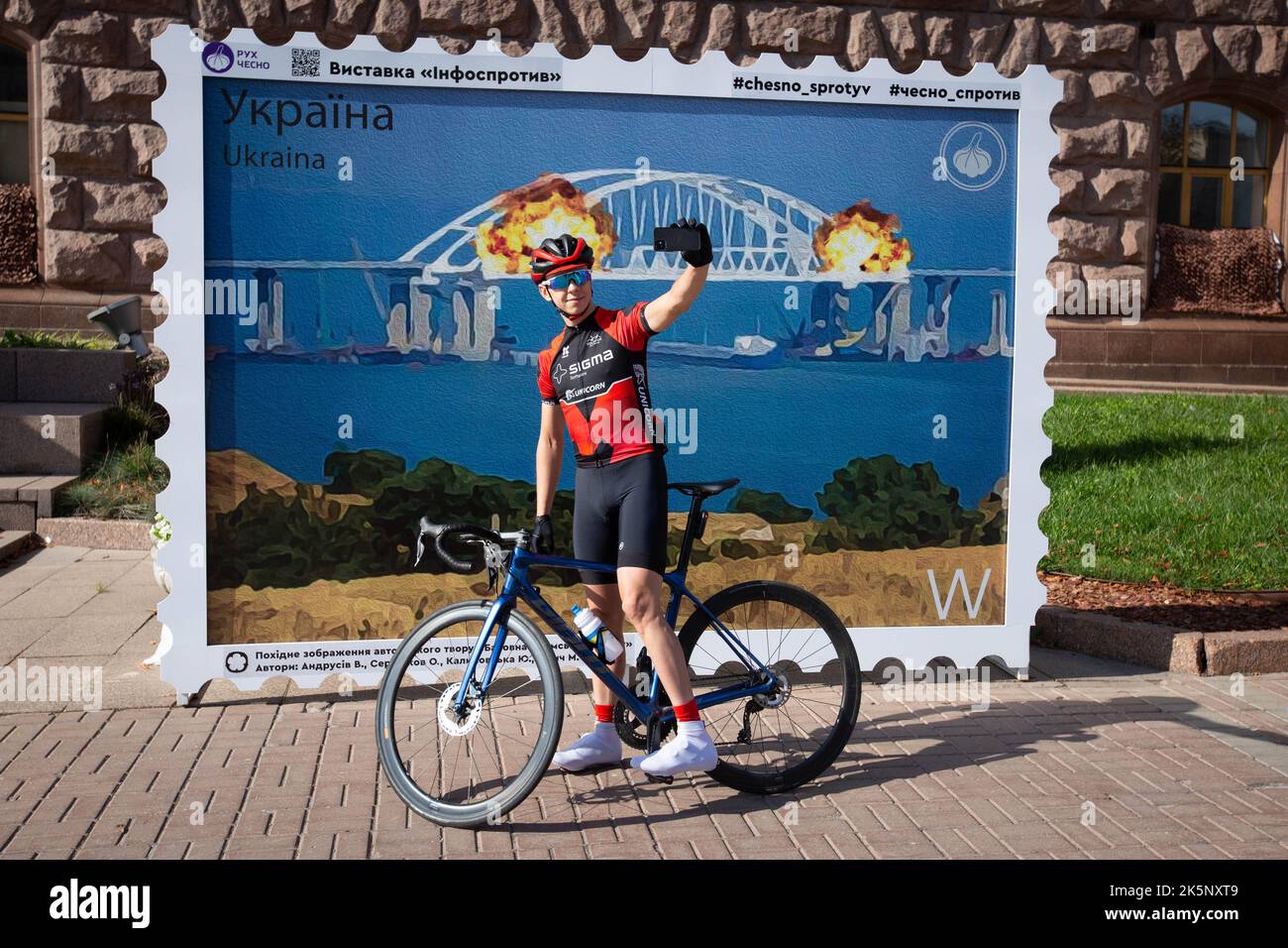 Kiev, Ukraine. 09th octobre 2022. Un homme prend un selfie avec un modèle de timbre représentant le pont de Crimée en feu en arrière-plan, dans le centre de Kiev. Sur 8 octobre, une explosion s'est produite sur le pont de Crimée construit par la Russie reliant la Russie à la péninsule de Crimée occupée par lui, endommageant une partie de la structure du pont. (Photo par Oleksii Chumachenko/SOPA Images/Sipa USA) crédit: SIPA USA/Alay Live News Banque D'Images