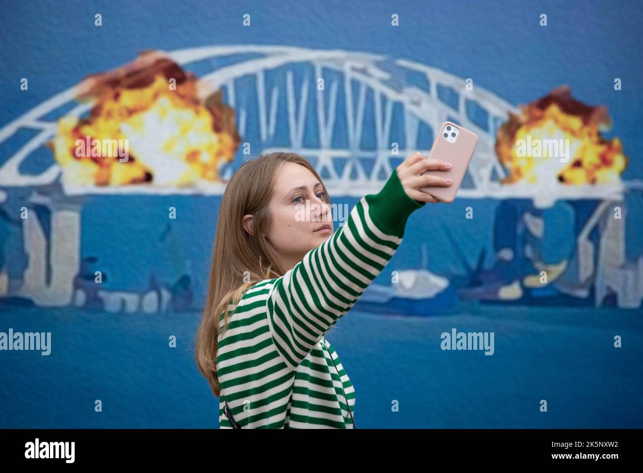 Kiev, Ukraine. 09th octobre 2022. Une femme prend un selfie devant une maquette d'un timbre représentant le pont en feu de Crimée en arrière-plan, dans le centre de Kiev. Sur 8 octobre, une explosion s'est produite sur le pont de Crimée construit par la Russie reliant la Russie à la péninsule de Crimée occupée par lui, endommageant une partie de la structure du pont. (Photo par Oleksii Chumachenko/SOPA Images/Sipa USA) crédit: SIPA USA/Alay Live News Banque D'Images