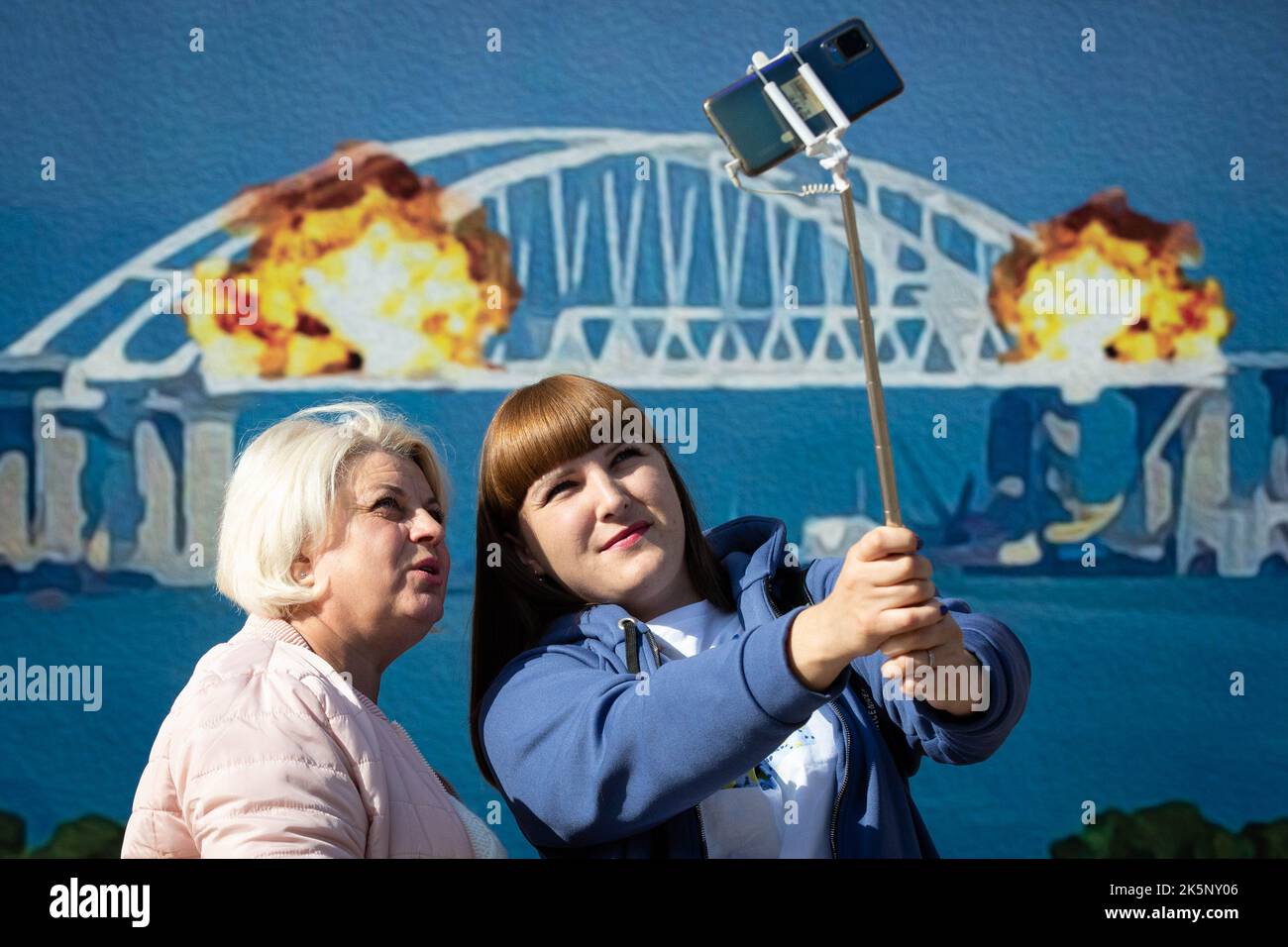 Kiev, Ukraine. 09th octobre 2022. Les femmes prennent un selfie avec un modèle de timbre représentant le pont de Crimée en feu en arrière-plan, dans le centre de Kiev. Sur 8 octobre, une explosion s'est produite sur le pont de Crimée construit par la Russie reliant la Russie à la péninsule de Crimée occupée par lui, endommageant une partie de la structure du pont. (Photo par Oleksii Chumachenko/SOPA Images/Sipa USA) crédit: SIPA USA/Alay Live News Banque D'Images
