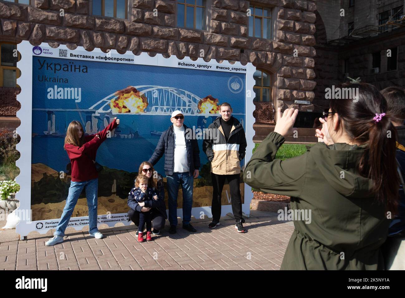 Kiev, Ukraine. 09th octobre 2022. Les gens sont photographiés avec un modèle de timbre représentant le pont en feu de Crimée en arrière-plan, dans le centre de Kiev. Sur 8 octobre, une explosion s'est produite sur le pont de Crimée construit par la Russie reliant la Russie à la péninsule de Crimée occupée par lui, endommageant une partie de la structure du pont. (Photo par Oleksii Chumachenko/SOPA Images/Sipa USA) crédit: SIPA USA/Alay Live News Banque D'Images