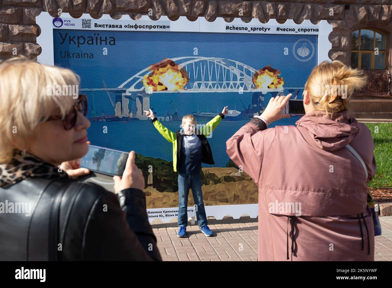 Kiev, Ukraine. 9th octobre 2022. Les femmes prennent des photos d'un garçon avec un modèle de timbre représentant le pont de Crimée en feu en arrière-plan, dans le centre de Kiev. Sur 8 octobre, une explosion s'est produite sur le pont de Crimée construit par la Russie reliant la Russie à la péninsule de Crimée occupée par lui, endommageant une partie de la structure du pont. (Credit image: © Oleksii Chumachenko/SOPA Images via ZUMA Press Wire) Credit: ZUMA Press, Inc./Alamy Live News Banque D'Images