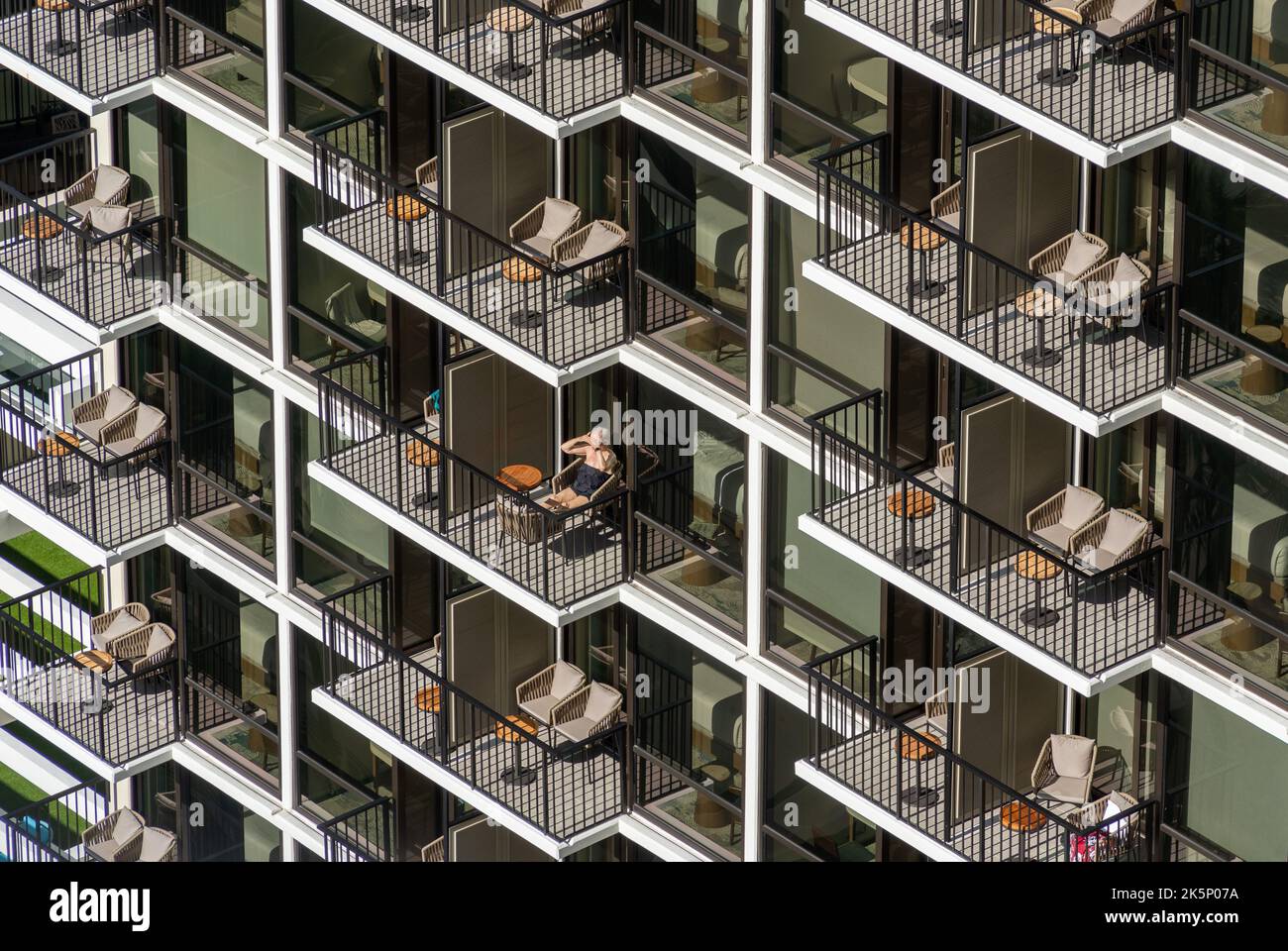 Un gros plan de balcons d'appartement similaires avec des meubles d'extérieur et un homme bronzage Banque D'Images