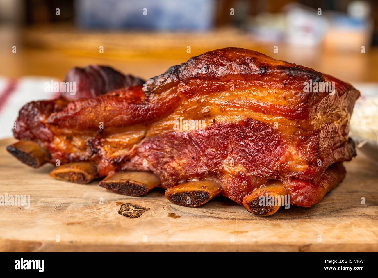 Morceau de côte de porc juteuse avec croûte croustillante sur le plan de cuisine en bois sur la table, en gros plan. Banque D'Images