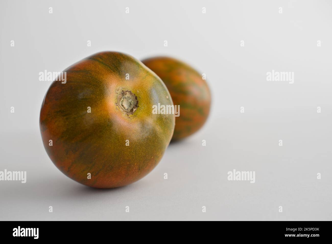 deux tomates tigrées rouges sur fond blanc Banque D'Images