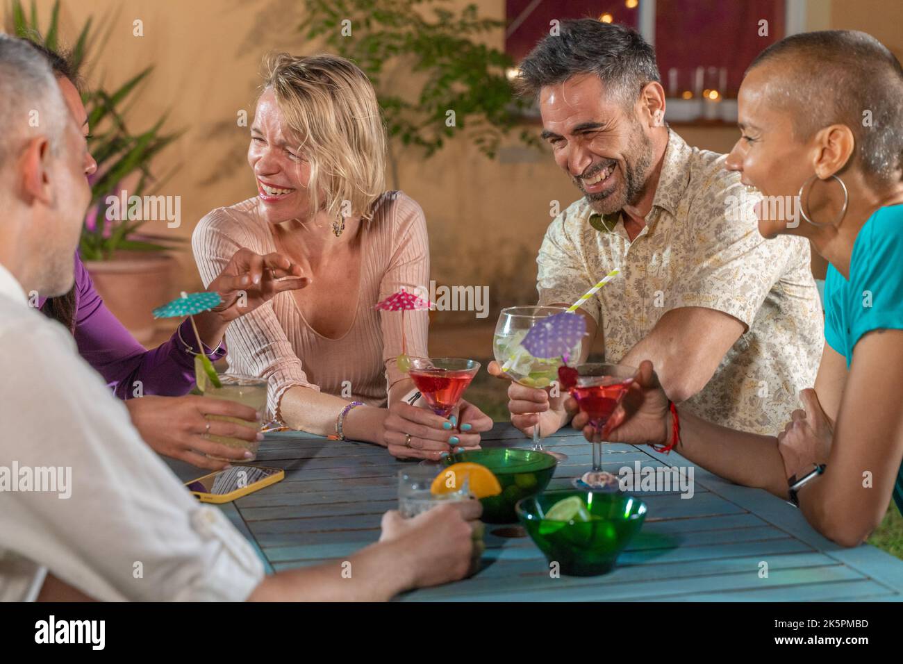 Groupe d'amis multiculturels et joyeux lors de la soirée en train de boire des cocktails et de s'amuser ensemble. Prendre un verre dans la vie nocturne. Banque D'Images