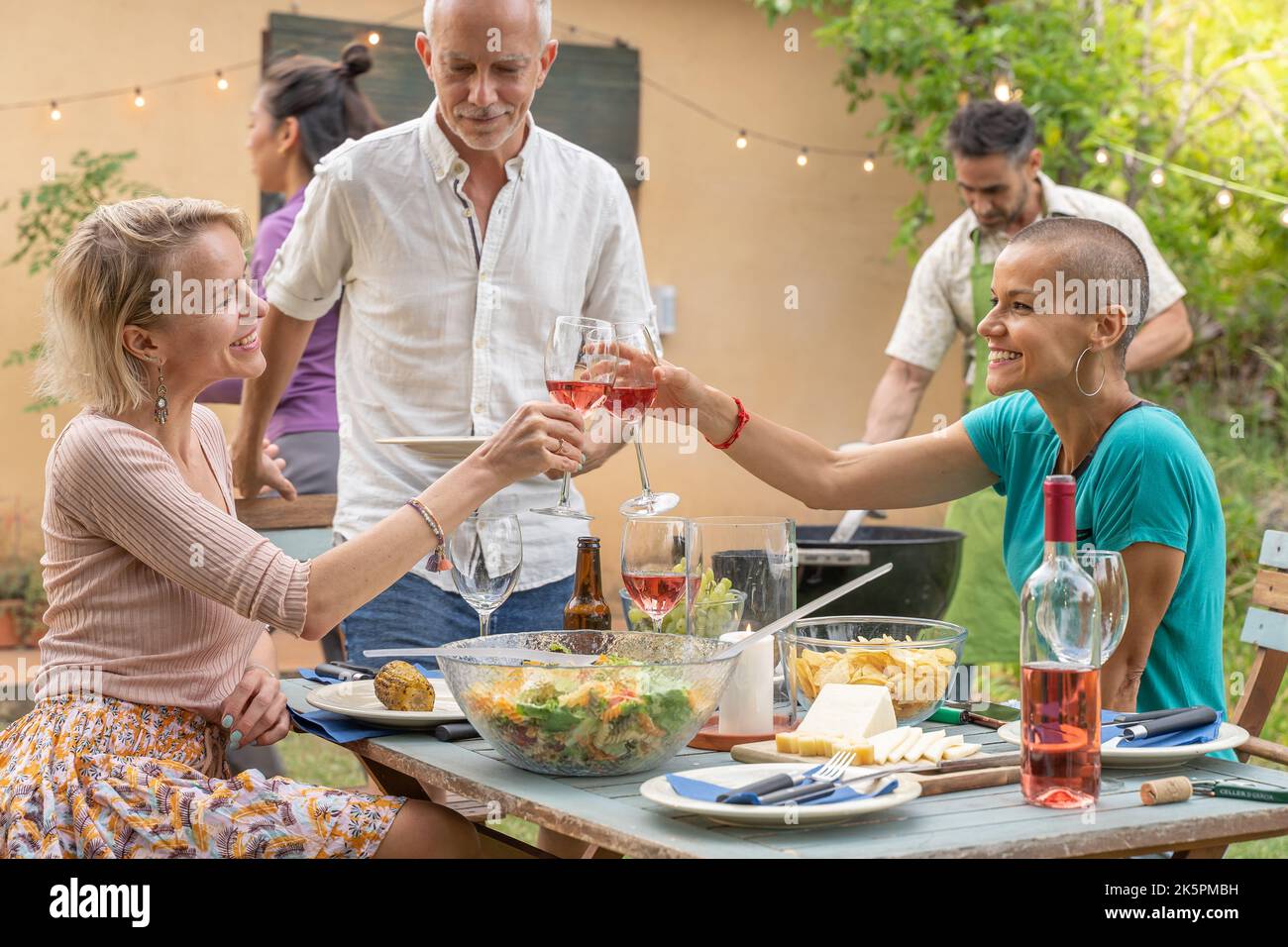 Des amis joyeux se promener autour de la table au restaurant sur le patio de la maison. Banque D'Images