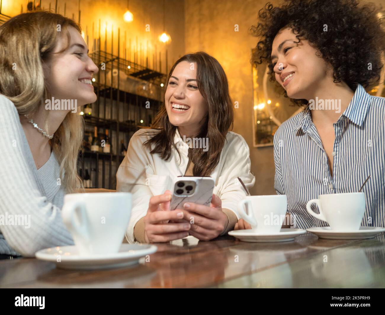 Trois amis dans un café bavardent avec plaisir Banque D'Images