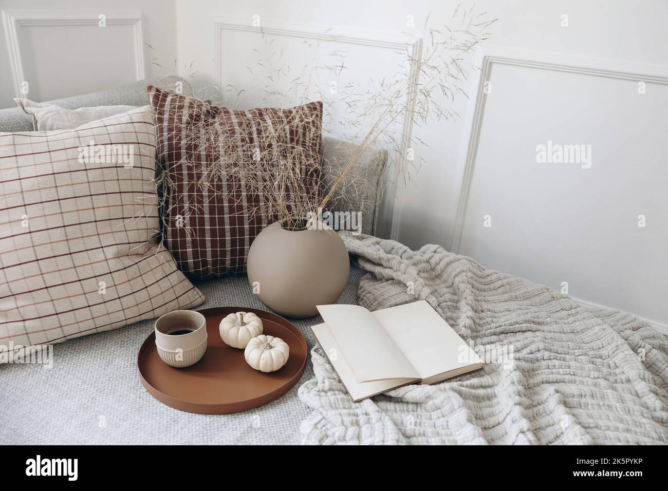 Petit déjeuner au lit, canapé papeterie scène maquette. Tasse de café, citrouilles. Livre ouvert. Tasse de café sur plateau. Sécher le bouquet d'herbe dans un vase en forme de boule Banque D'Images