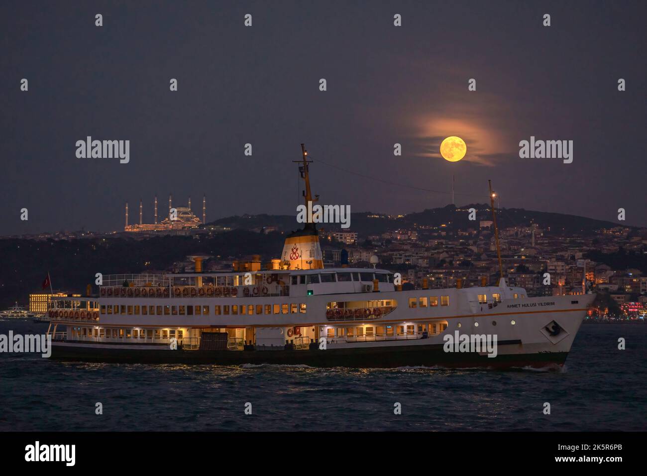 Istanbul, Turquie. 09th octobre 2022. Les lignes de la ville ferry passant par le Bosphore vu avec la pleine lune apparaissant dans le ciel et la mosquée Camlica dans la soirée. Crédit : SOPA Images Limited/Alamy Live News Banque D'Images
