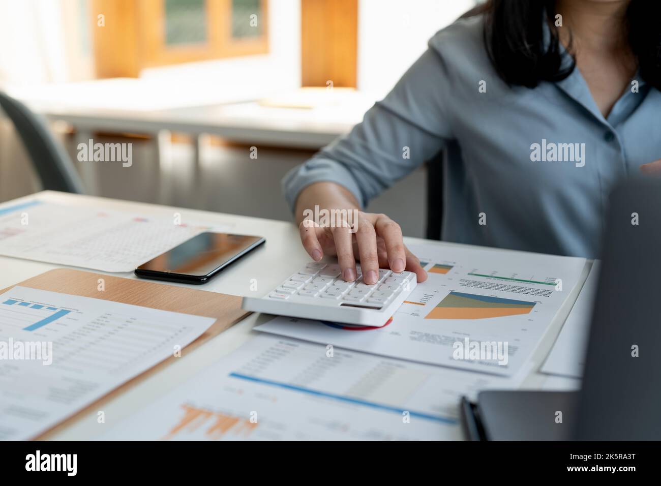 Femme d'affaires utilisant une calculatrice pour calculer les chiffres du rapport financier sur bureau, concept de comptabilité financière. Banque D'Images