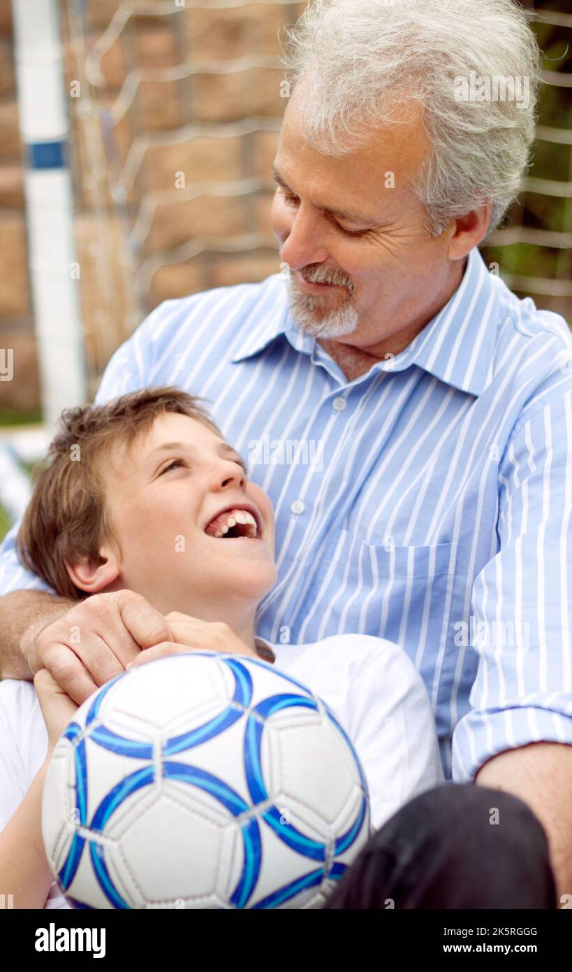 Je veux être super au football comme mon père. Père et fils heureux jouant autour avec un ballon de football. Banque D'Images