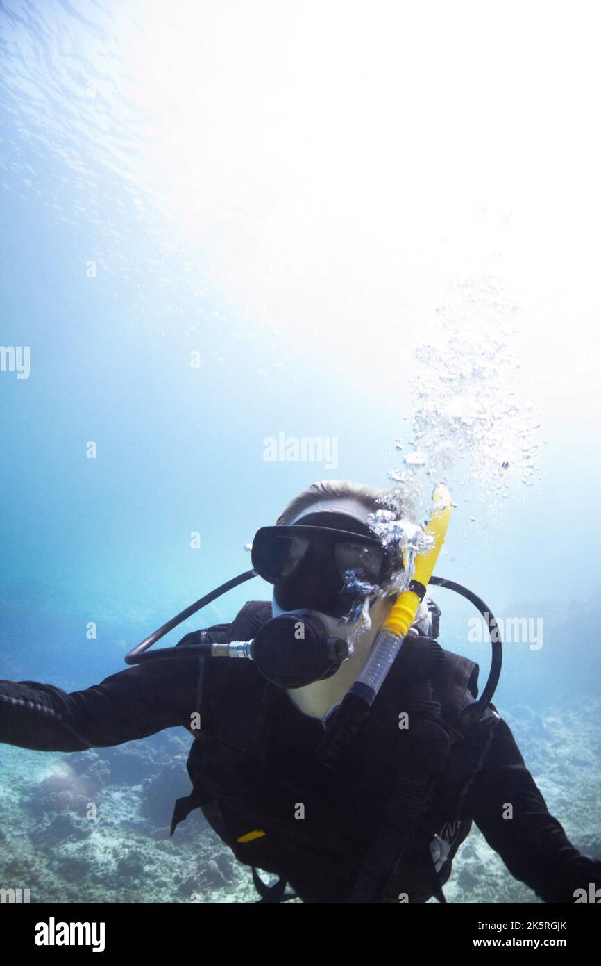 Trouver des loisirs sous les vagues. Une jeune femme plongée sous-marine dans le magnifique océan avec le soleil brillant qui brille à travers l'eau - CopySpace. Banque D'Images