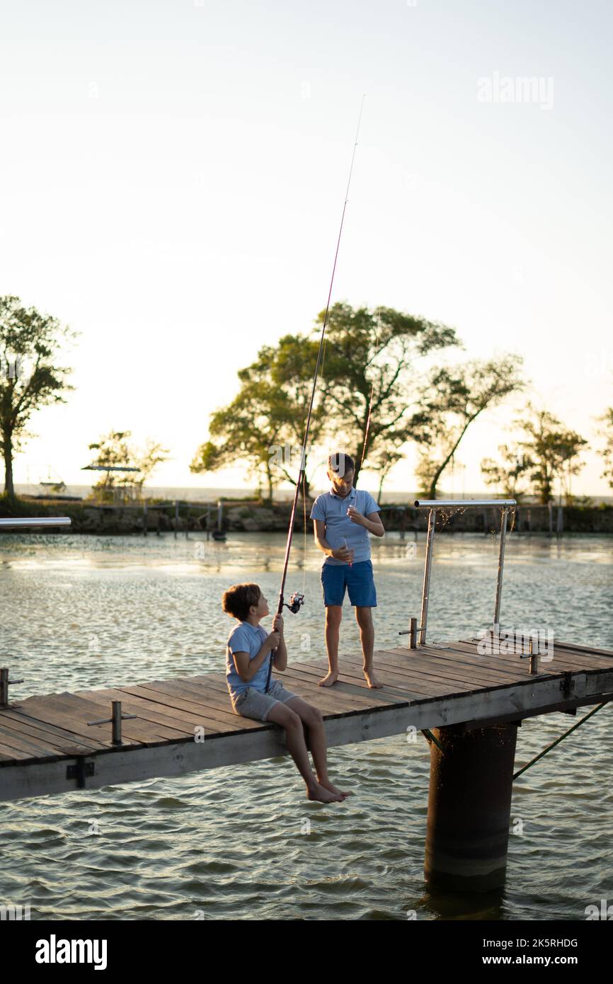 Les garçons pêchent au coucher du soleil sur le lac. Loisirs et loisirs d'été Banque D'Images