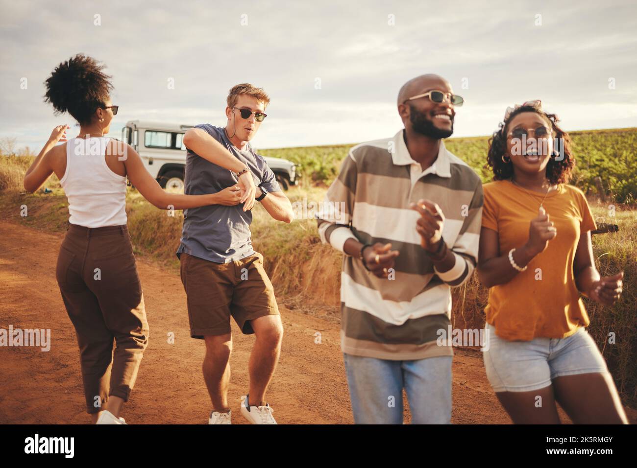 Liberté, voyage et danse avec des amis en voyage en campagne pour la fête, l'été et la fête. Aventure, voyage et vacances avec un jeune groupe Banque D'Images