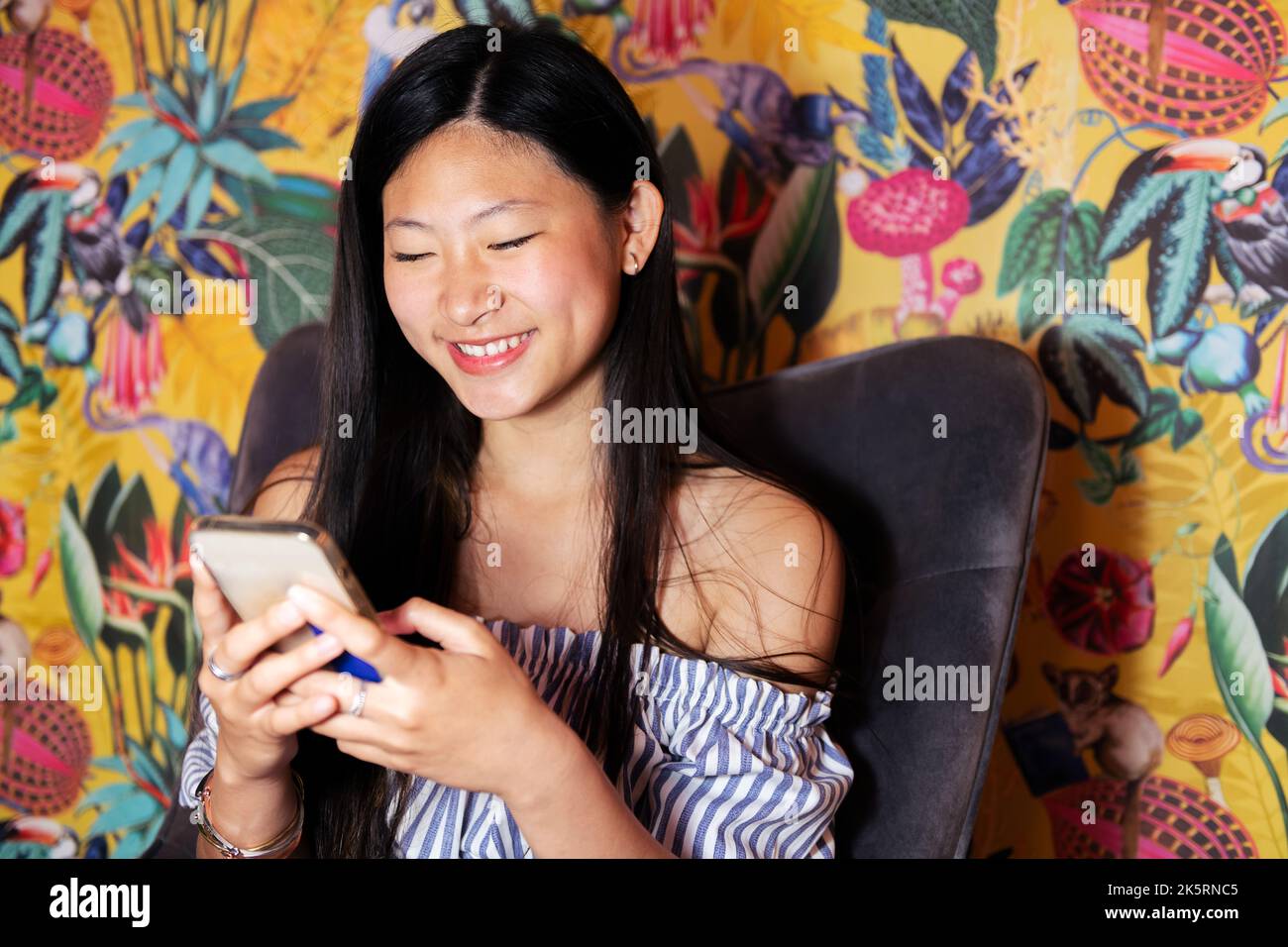 femme utilisant un téléphone portable assis dans un fauteuil Banque D'Images