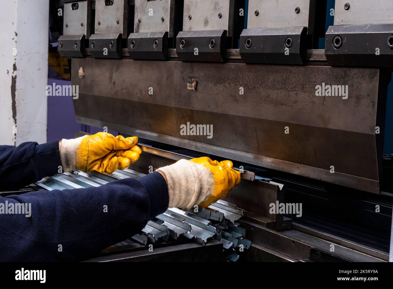 frein de presse hydraulique ou machine à plier pour tôle plate. Travailleur qui plie la tôle sur la machine de pliage. Banque D'Images