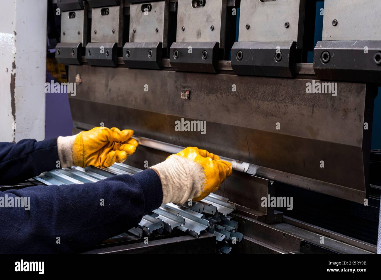 frein de presse hydraulique ou machine à plier pour tôle plate. Travailleur qui plie la tôle sur la machine de pliage. Banque D'Images
