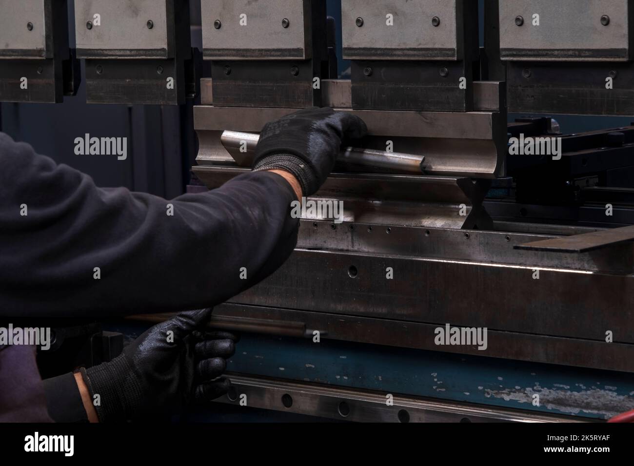 frein de presse hydraulique ou machine à plier pour tôle plate. Travailleur qui plie la tôle sur la machine de pliage. Banque D'Images