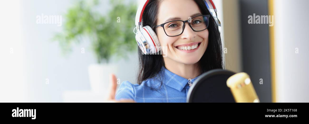 Une radio-hôte femme dans un casque avec microphone tient les pouces vers le haut Banque D'Images