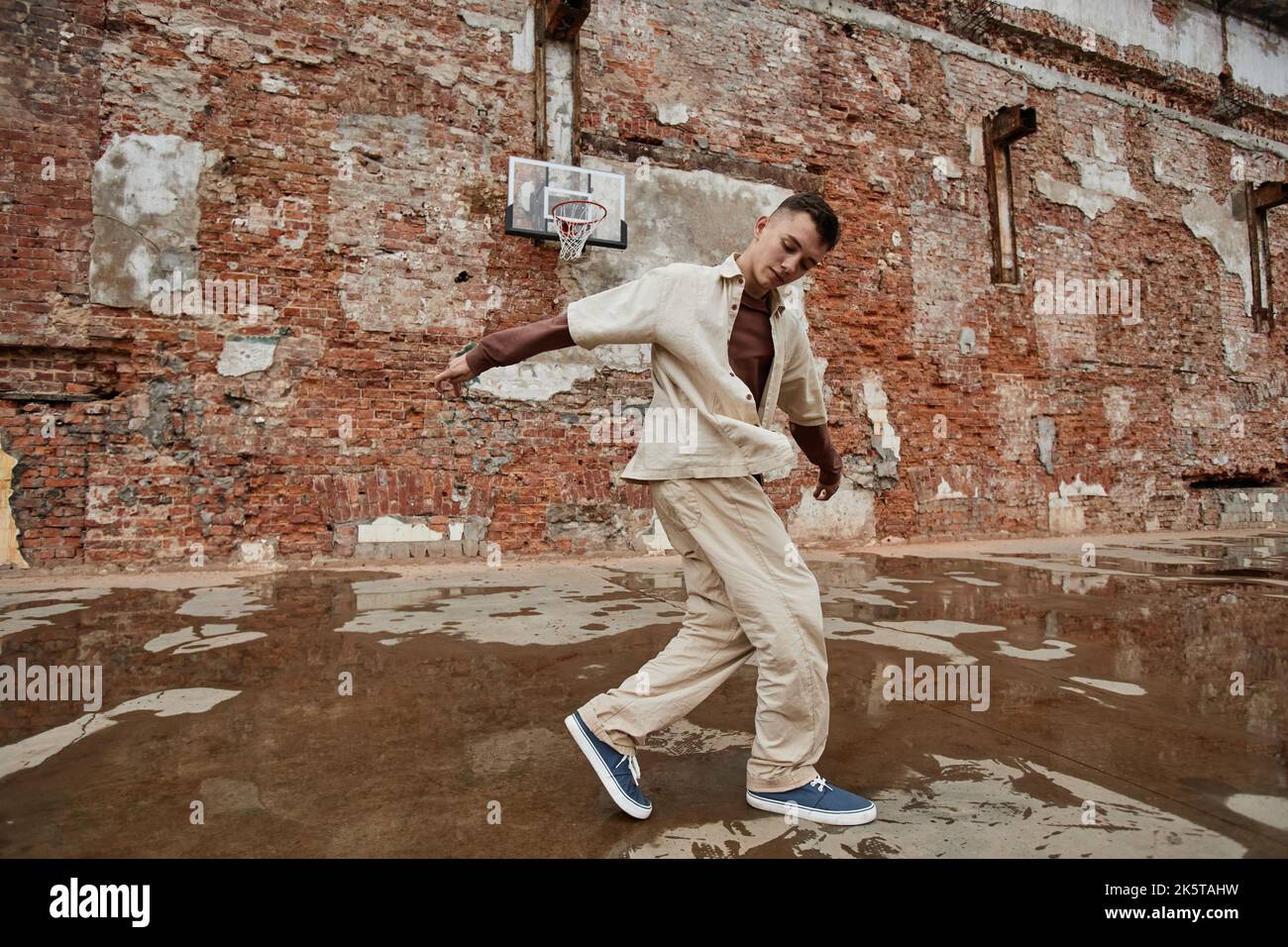 Image figée de breakdancer masculin en train de jouer contre un mur de briques déchiqueuse à l'extérieur, espace de copie Banque D'Images