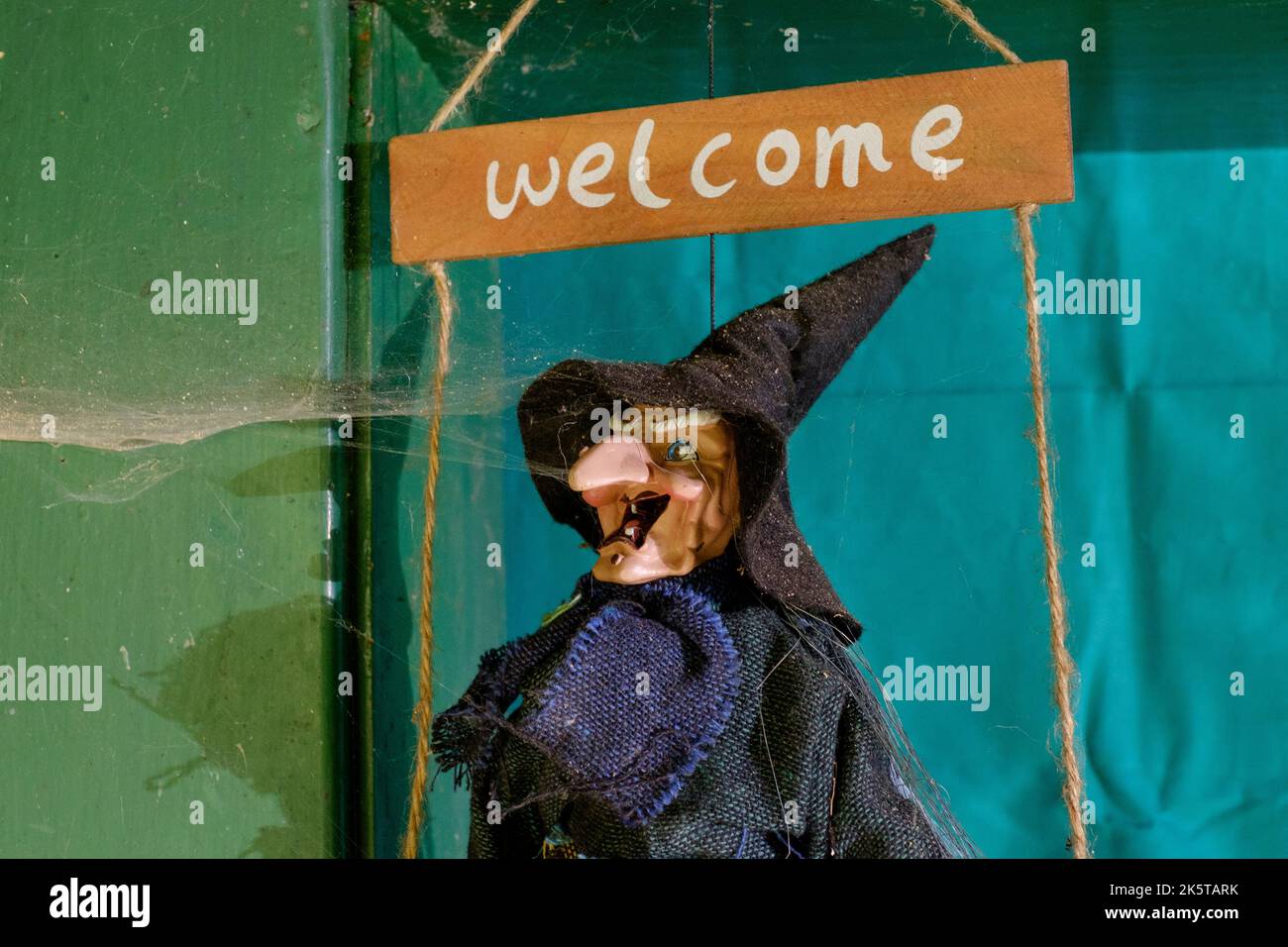 affiche de bienvenue de style halloween avec sorcière dans un chapeau pointu accroché dans la porte de la maison couverte par toile d'araignée Banque D'Images