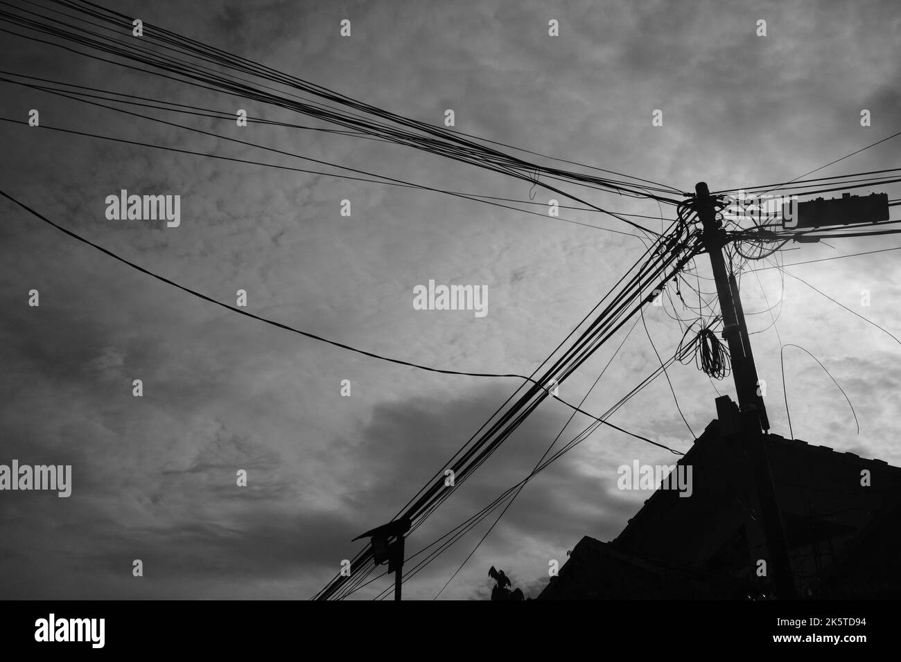 Poteau électrique et toit, Silhouette photo de poteaux électriques pleins de fils derrière le toit d'une maison dans la région de Cikancung, Indonésie Banque D'Images