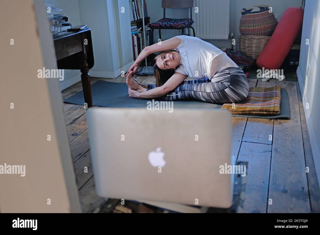 Une femme à la maison faisant du yoga et regardant un cours en ligne. Banque D'Images