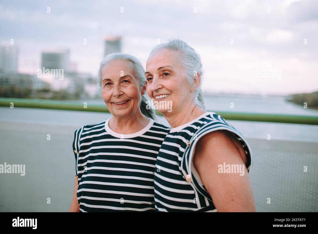 Portrait de femmes âgées heureuses, jumeaux dans les mêmes vêtements, marchant sur le pont de la ville. Banque D'Images