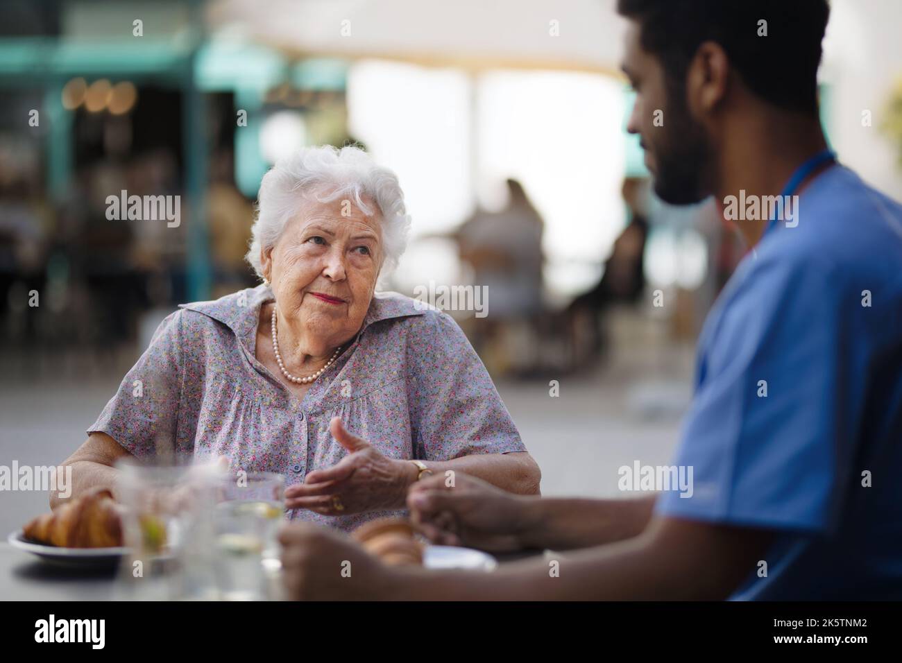 Soignant prenant le petit déjeuner avec son client au café. Banque D'Images