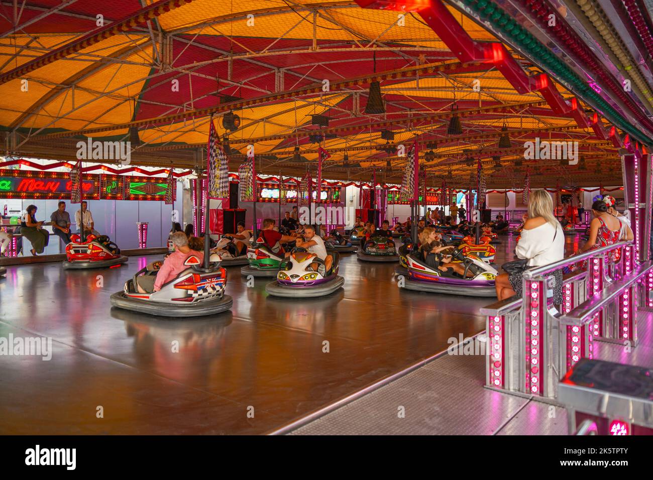 Les enfants avec leurs parents s'amusent dans les voitures tamponneuses d'une foire dans la ville espagnole de Fuengirola, Costa del sol, Espagne. Banque D'Images