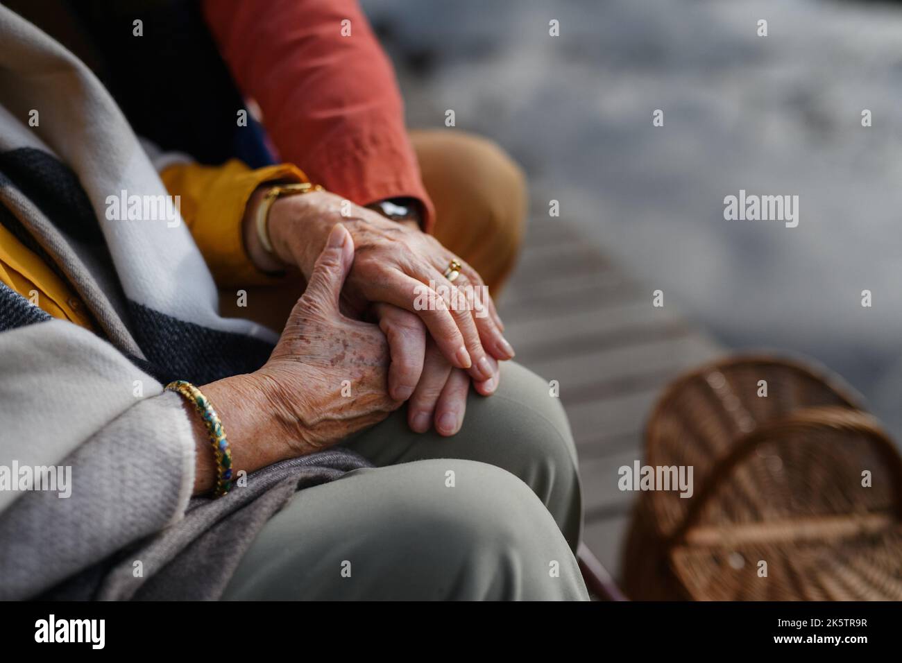 Gros plan d'un couple senior se tenant l'un contre l'autre main et assis près du lac. Banque D'Images