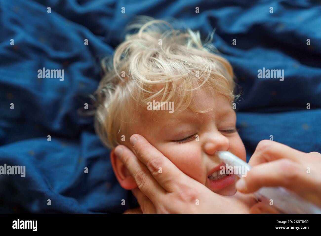 Gros plan du parent tenant son fils et utilisant un extracteur de snot. Banque D'Images