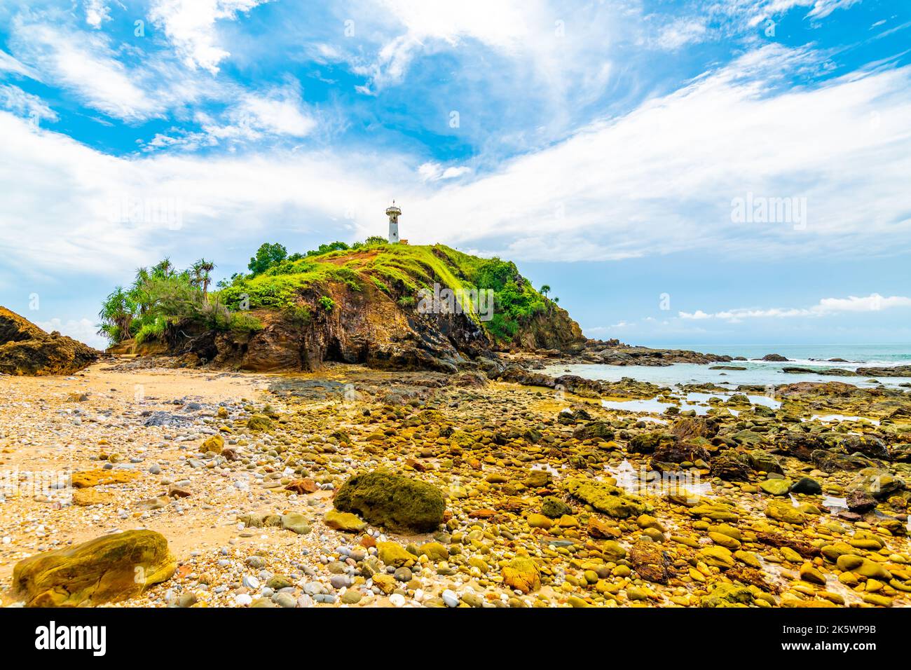 Phare sur le rocher au parc national de Mu Ko Lanta, Thaïlande. Vue de la plage avec pierres. Météo d'été, ciel bleu avec nuages. Banque D'Images