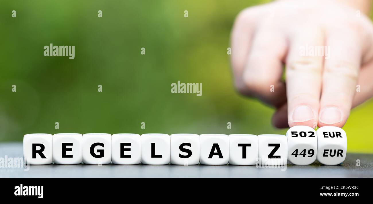 La main tourne les dés et change l'expression allemande 'Regelsatz 449 Euro' en 'Regelsatz 502 Euro' (Regelsatz = taux standard). Symbole d'augmentation de Banque D'Images