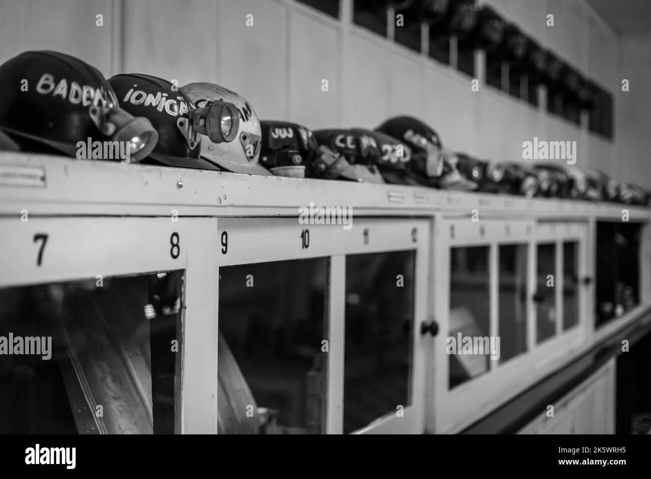 Prise de vue en niveaux de gris de casques avec lampes de poche placées sur une armoire en bois Banque D'Images