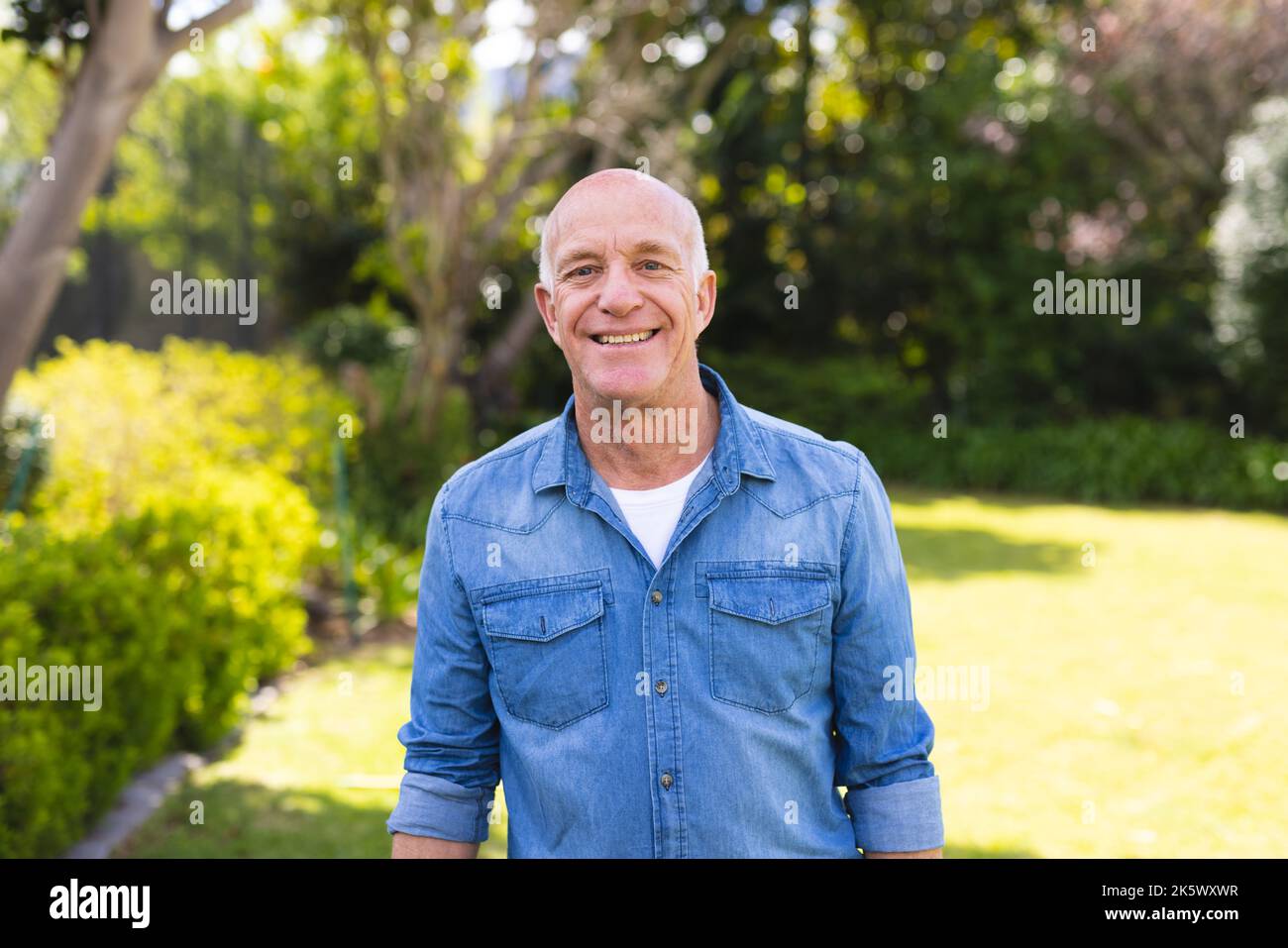 Portrait d'hommes blancs âgés portant une chemise bleue et se tenant dans le jardin Banque D'Images
